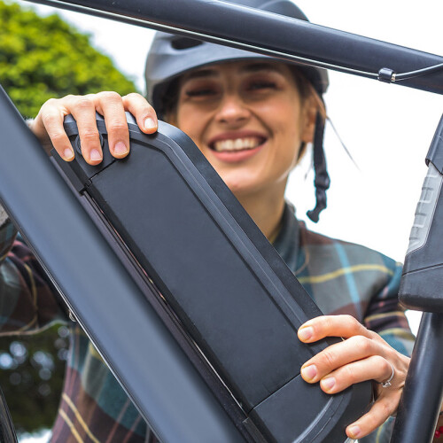 Frau mit Helm tauscht einen Fahrradakku aus