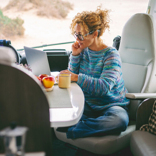 Woman sitting in a vehicle at a laptop