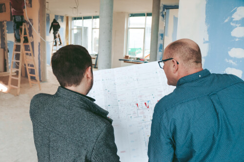Two men look at the sketch of the new building