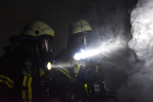 Two firefighters with torches in the dark