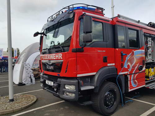 Ein roter Feuerwehrwagen mit blauem Ladekabel
