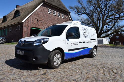 Ein Milchtransporter vor einem Reetdachhaus