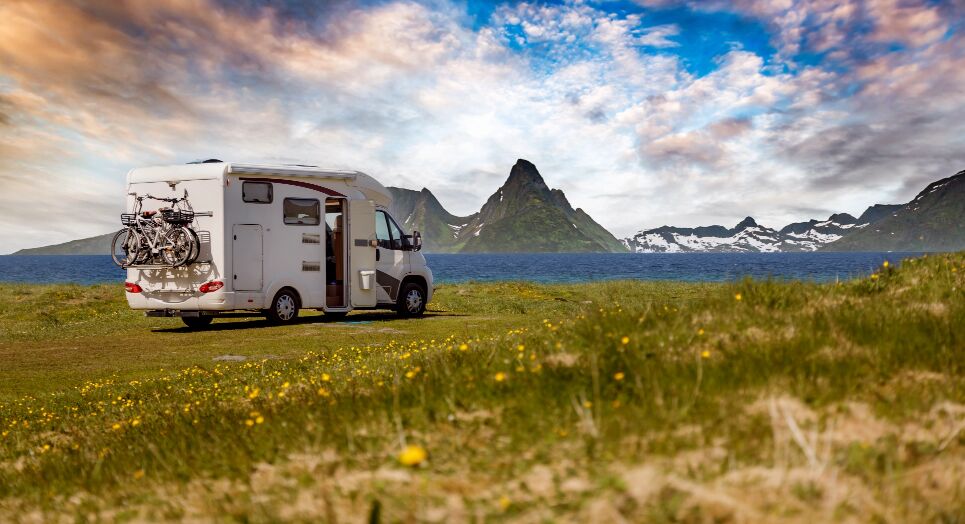 Camper standing by the water in front of mountains