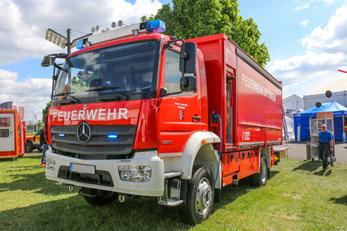 A red fire engine stands on a green area in front of the exhibition grounds