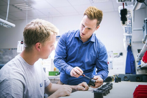 A man explains something to a trainee with a screwdriver