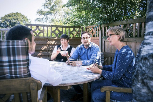 Four people sitting at a garden table and talking