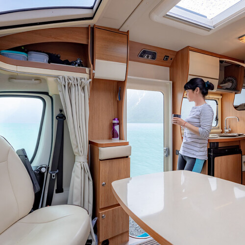 Woman standing in the camper and looking at the water